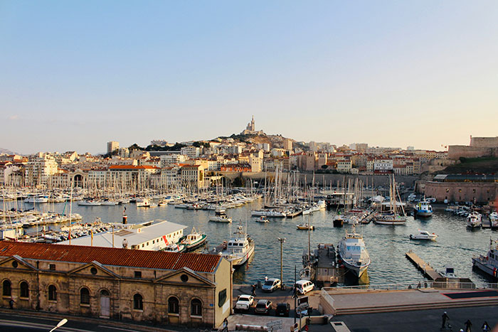 Marseille harbor with boats and cityscape at sunset, highlighting solo female travelers places not recommended.