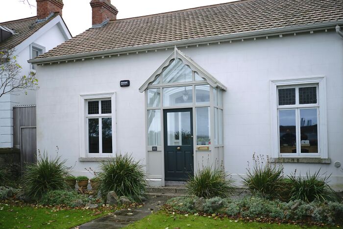 Cozy white house with a glass porch, green door, and garden, symbolizing rehoming a dog after being abandoned abroad. Cozy white house with a glass porch, green door, and garden, symbolizing rehoming a dog after being abandoned abroad.