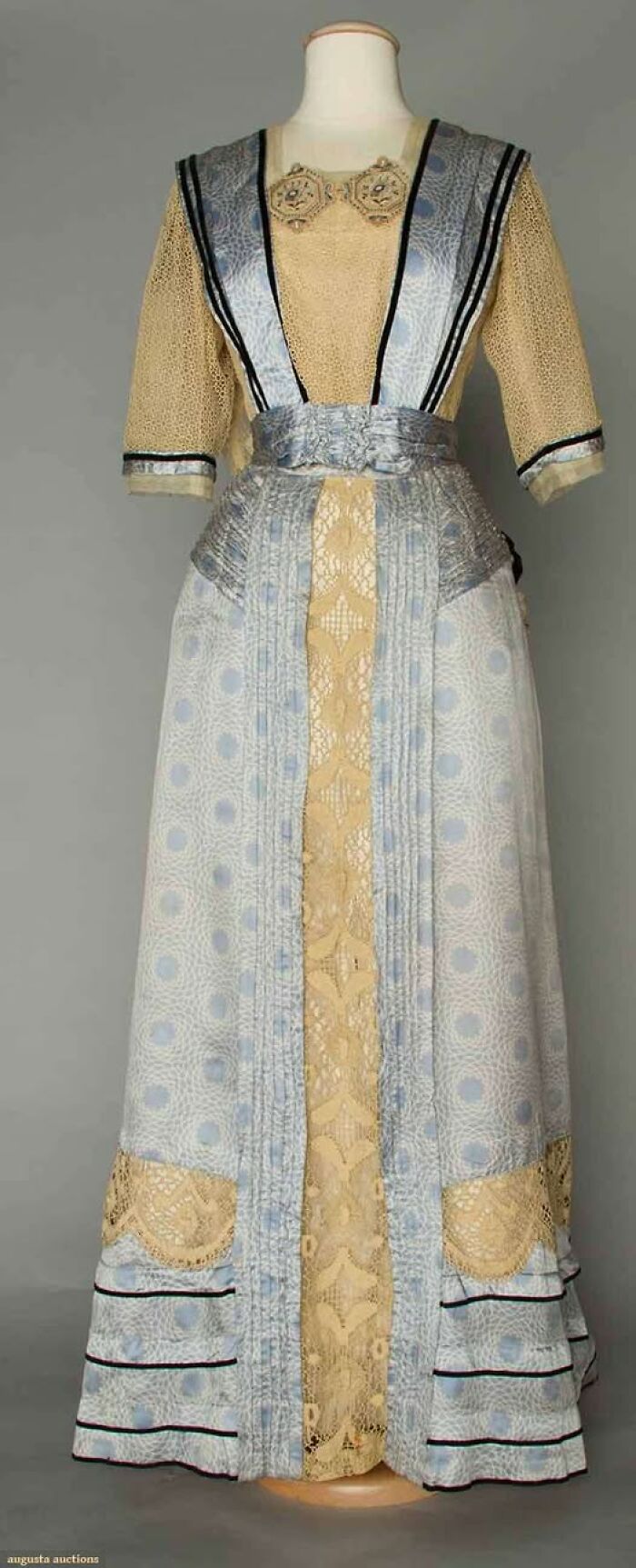Victorian-Edwardian dress on mannequin featuring lace and blue patterned fabric with black trim detailing.
