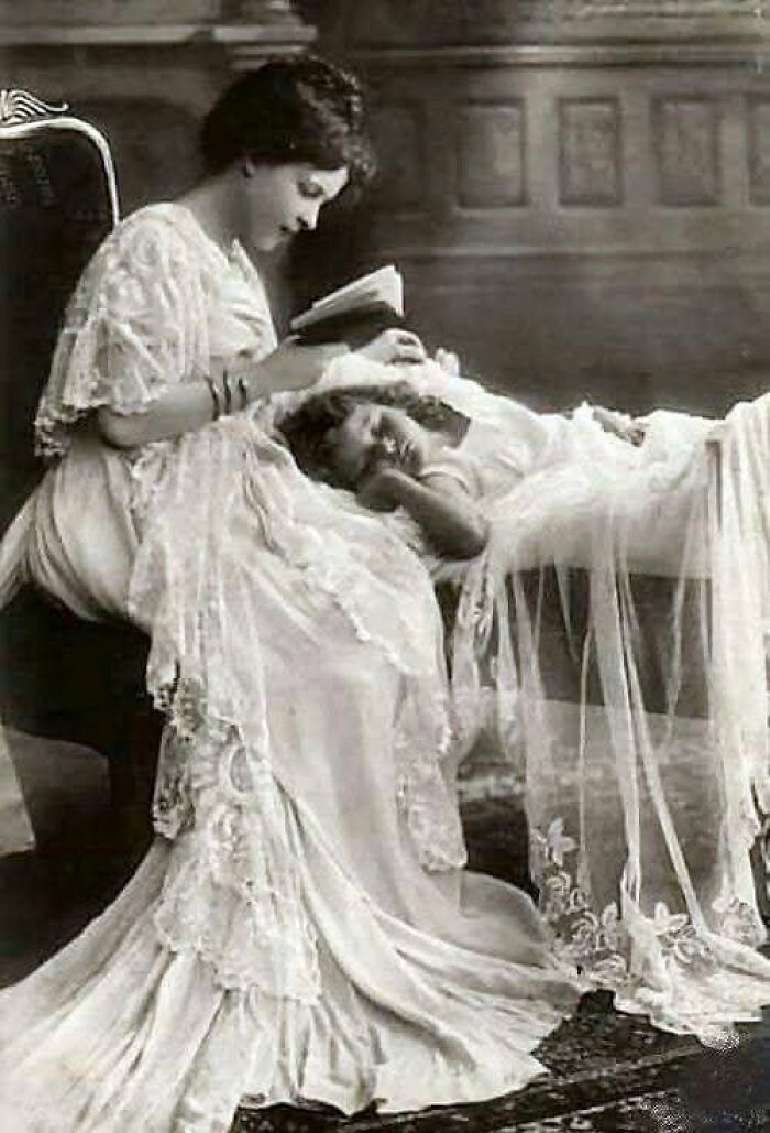 Victorian-Edwardian pictures showing a woman in lace dress reading to a child resting on a table with a lace cloth.