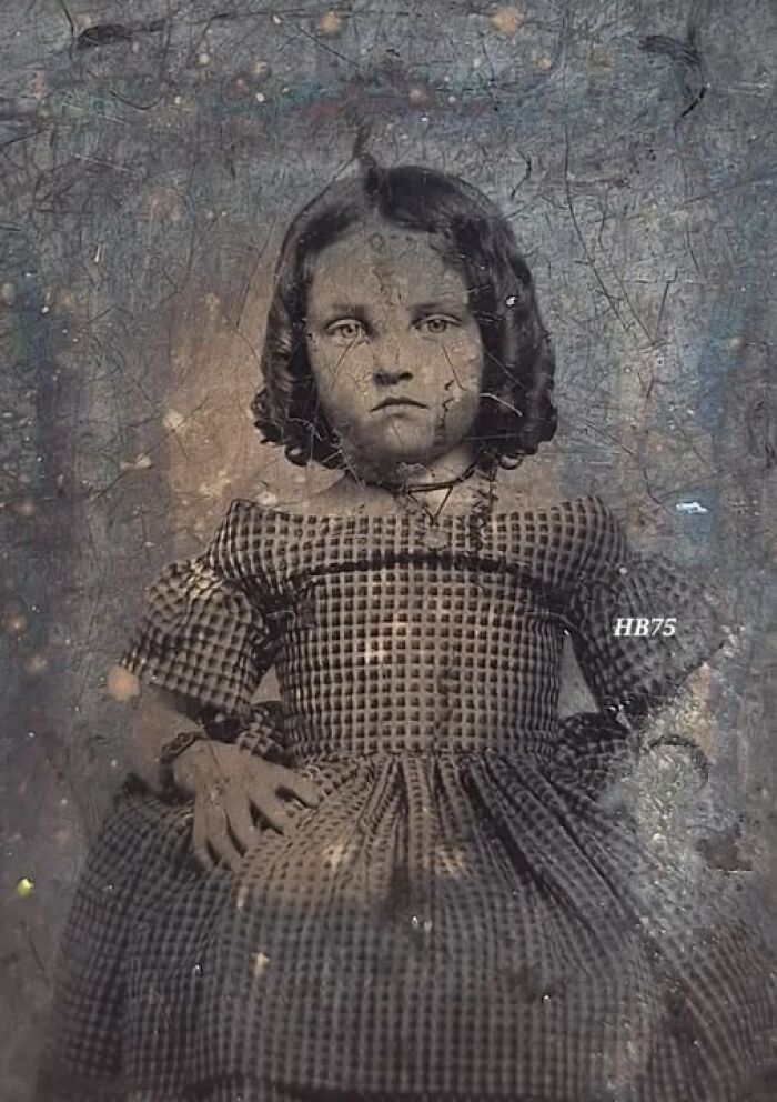 Victorian-Edwardian pictures of a young girl in a patterned dress with serious expression in an old vintage photograph.