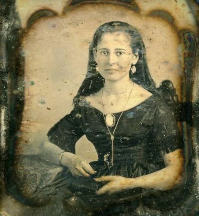 Victorian-Edwardian picture of a seated woman wearing period dress and jewelry, captured in an old photographic portrait.