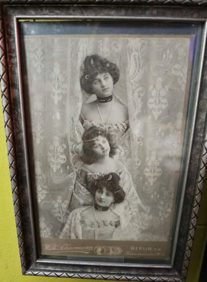 Victorian-Edwardian pictures of three women in vintage lace dresses and ornate hairstyles in a framed black and white photo.