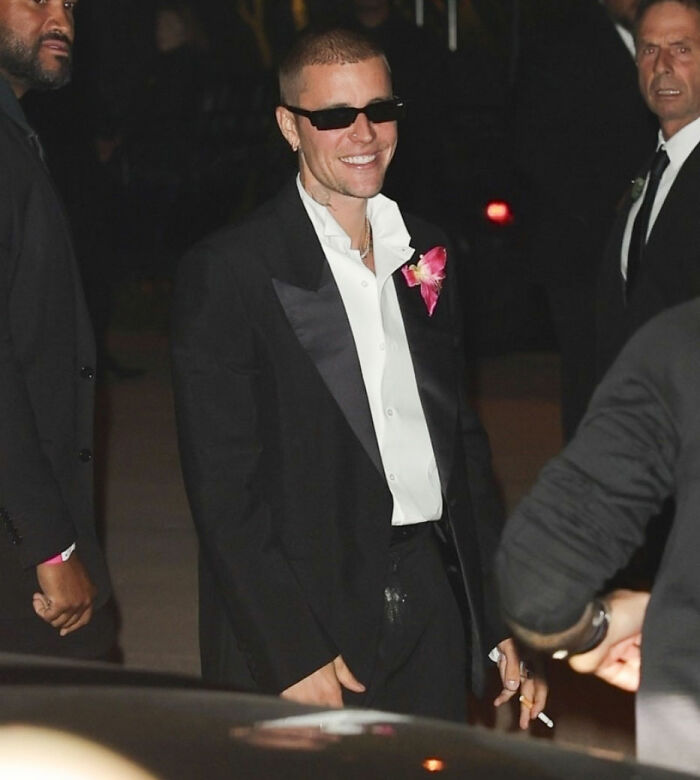 Justin Bieber wearing sunglasses and a tuxedo with fans noticing something on his c****h at a nighttime event. Justin Bieber wearing sunglasses and a tuxedo with fans noticing something on his c****h at a nighttime event.