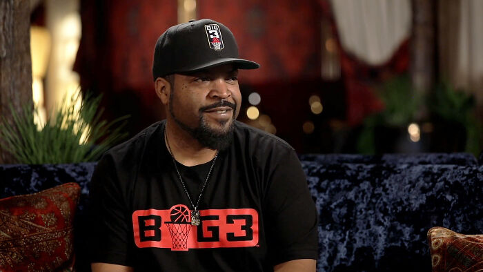 Man wearing a black Big3 shirt and cap sitting on a couch, sharing insider experiences about nepo babies.