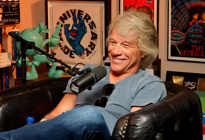 Man with gray hair smiling during a podcast interview, sharing insider experiences of nepo babies in an informal setting.