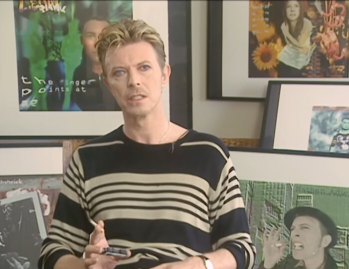 Man in striped sweater sitting indoors surrounded by vintage posters, illustrating insane patient behavior under anesthesia effects.