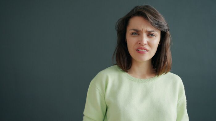 Young woman in a green sweater looking confused, relating to confronting a family over watermark removal on photos. Young woman in a green sweater looking confused, relating to confronting a family over watermark removal on photos.