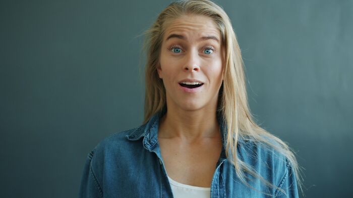 Surprised woman with blue eyes and blonde hair wearing denim shirt illustrating kids doing something weird passed down from parents.