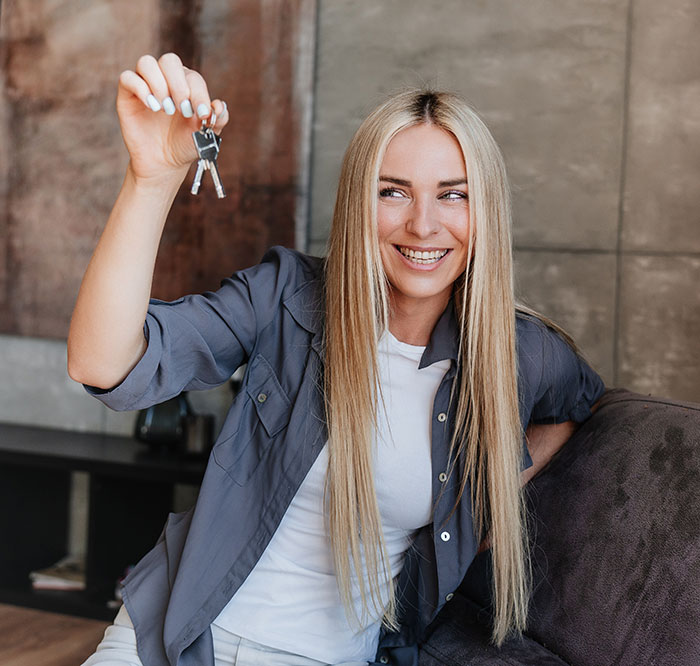Smiling young woman holding a set of keys indoors, highlighting unhinged things men didn’t want in women.
