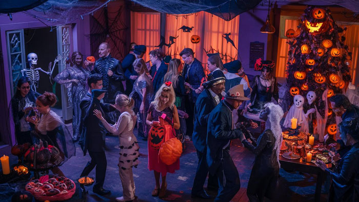 Halloween party with dozens of guests in costumes, highlighting noise and safety concerns brought by baby at family event.