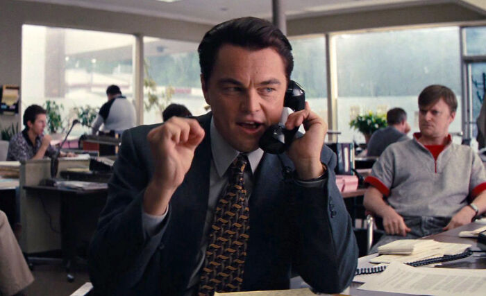 Man in suit talking on the phone in an office setting, representing nepo babies insider experiences in a corporate environment.