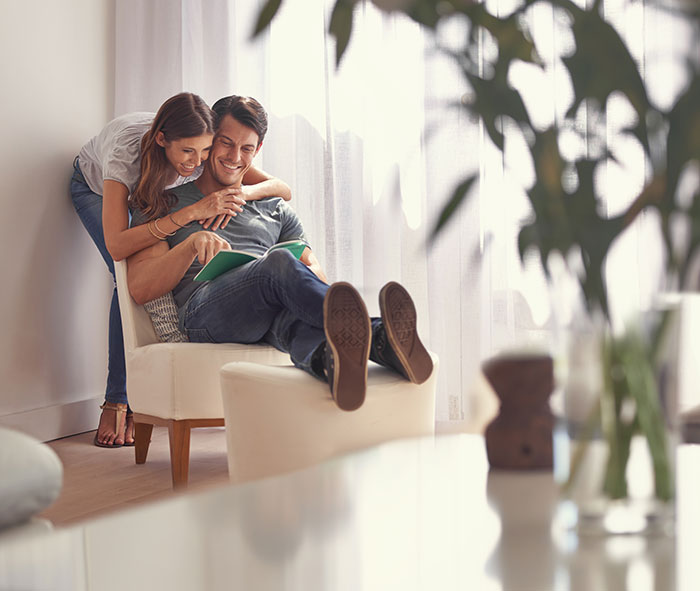 Couple sharing a joyful moment at home, highlighting a guy secretly giving his sister a key to his girlfriend&rsquo;s house.