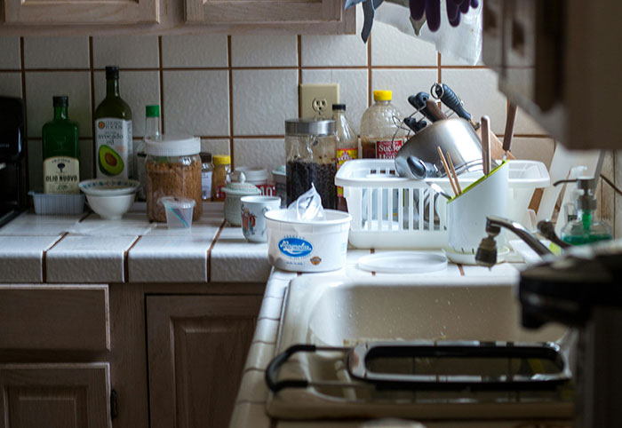 Cluttered kitchen counter with various jars, bottles, and utensils reflecting woman child lifestyle traits.