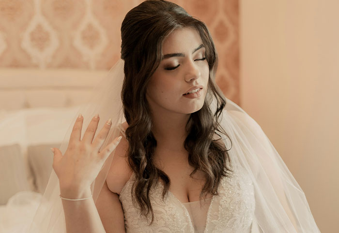 Young woman with long hair in a bridal gown expressing confident and playful woman child energy indoors
