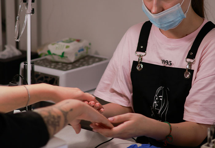 Woman child receiving a manicure, wearing a mask and casual clothes in a cozy nail salon setting.