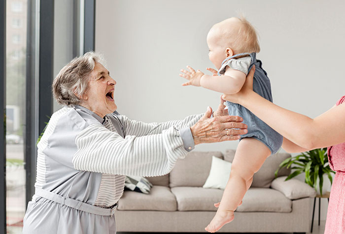Elderly MIL reaching out happily to a baby grandchild while other kids are treated like burdens at home.