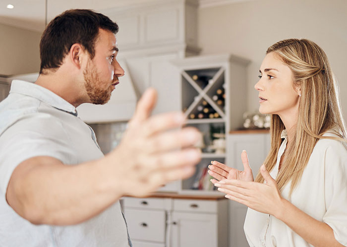 Woman and jobless partner arguing in a kitchen, highlighting a relationship conflict about financial contribution and value.