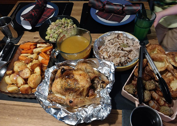 Traditional Christmas spread with roasted chicken, vegetables, stuffing, and gravy, highlighting foreign holiday cuisine elements.
