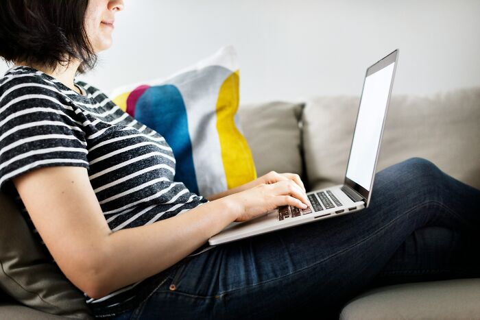Woman sitting on couch using laptop, concerned about lonely widower fixating and appearing everywhere she goes.
