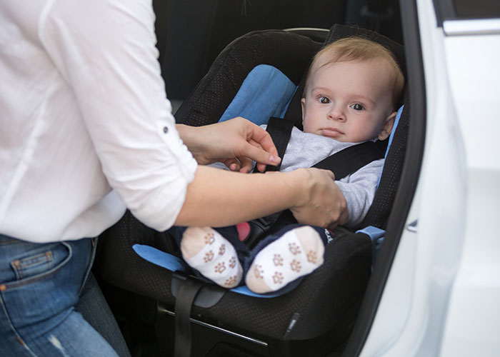 Man upset as nurse girlfriend prioritizes baby and dogs during car crash, fastening baby in car seat with concern.