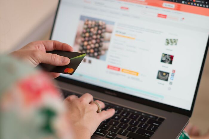Person holding a credit card while shopping online, illustrating how people fell for scams and their impact.