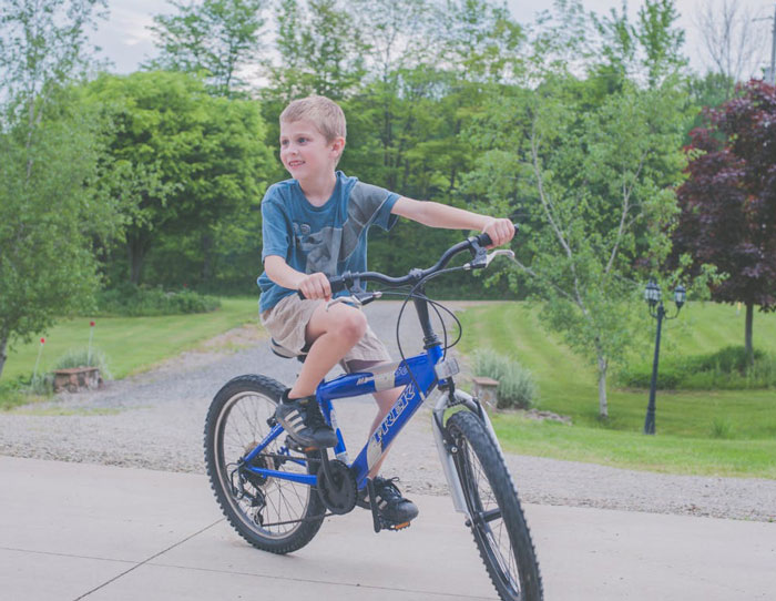 Young boy riding a blue bike outside as grandparents combine birthday and Christmas gift causing mom to feel scammed