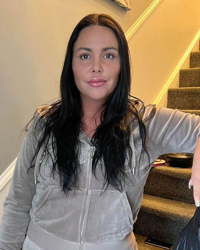 Woman with long dark hair in casual gray outfit sitting on stairs, related to BBL and tragic consequences for curves.