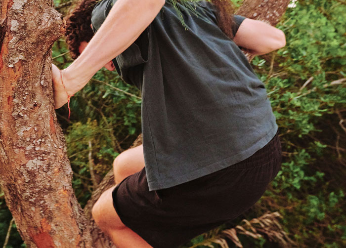Person struggling to climb a tree in a dense outdoor area, illustrating the worst night’s sleep due to the place.