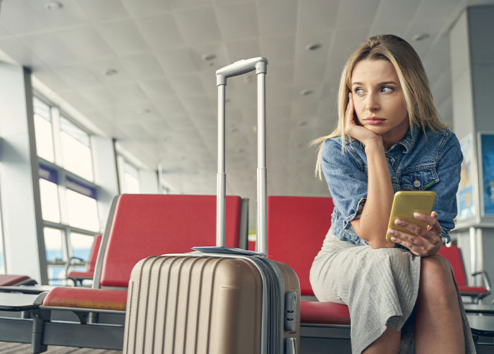 Young woman waiting at airport with luggage, looking restless and unable to sleep due to the place she is in.
