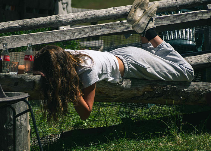 Person lying awkwardly on a wooden fence outdoors, illustrating the worst night’s sleep due to the uncomfortable place.