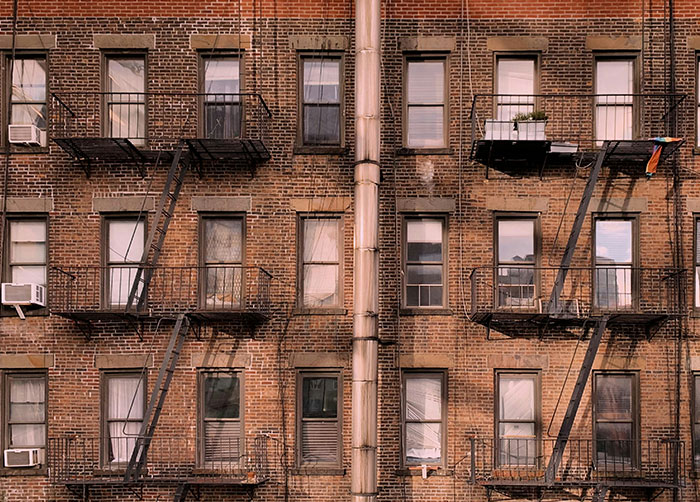 Brown brick apartment building with fire escapes symbolizing worst night's sleep in urban places.