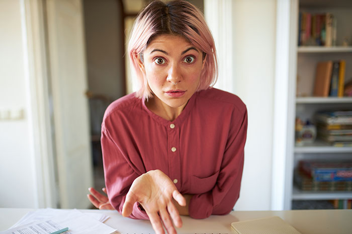 Woman with pink hair wearing a red shirt showing frustration, illustrating a lady going on a power trip at home.