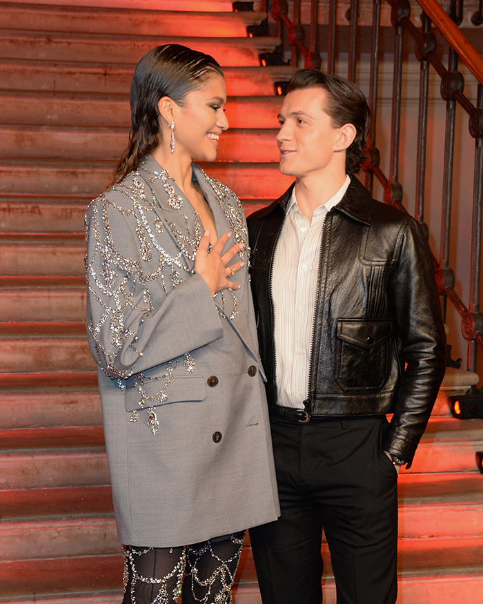 Zendaya and Tom Holland smiling at each other on stairs, sparking rumors about Zendaya being pregnant.