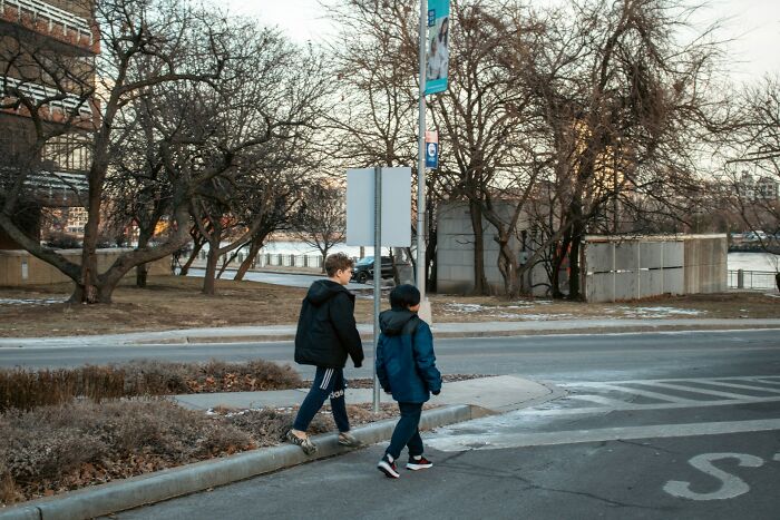 Two children walking near a road with bare trees at dusk, evoking haunting things truckers have seen on the road at night.