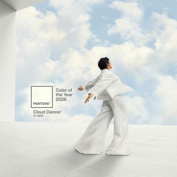 Person in white outfit posing against a cloudy sky background with Pantone&rsquo;s Color of the Year 2026 Cloud Dancer.