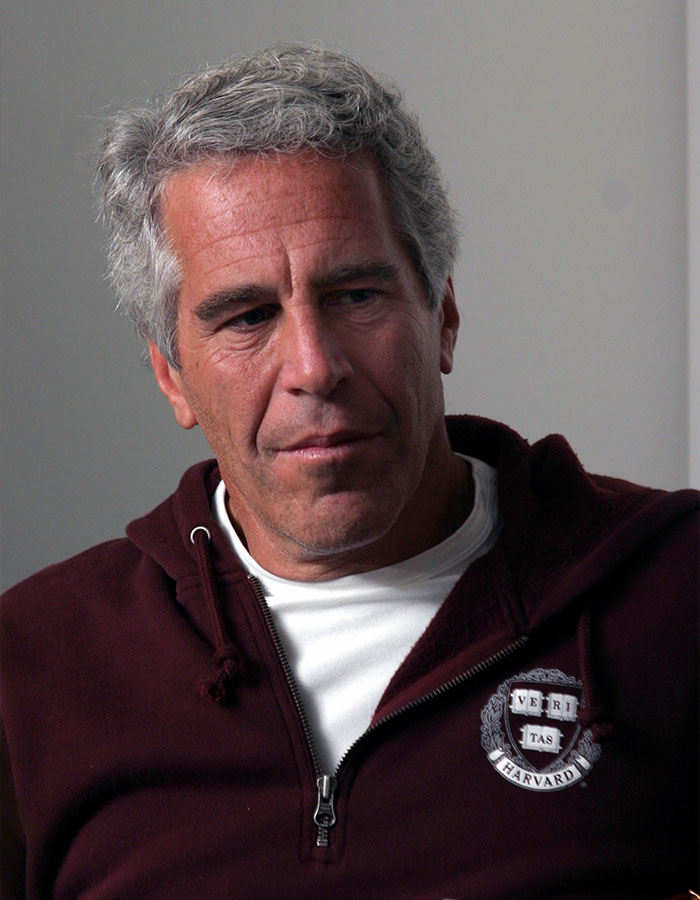 Jeffrey Epstein in a maroon Harvard sweatshirt, looking down pensively, linked to disturbing desk photo backlash after estate images release. Jeffrey Epstein in a maroon Harvard sweatshirt, looking down pensively, linked to disturbing desk photo backlash after estate images release.
