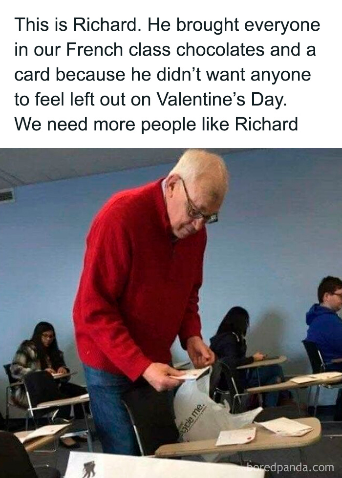 Older man in red sweater handing out chocolates and cards in a classroom, a sweet and wholesome moment to cleanse your feed.