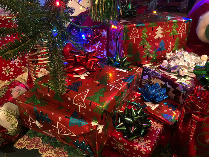 Wrapped Christmas presents with colorful bows under a tree, highlighting a man&rsquo;s contribution promise for kids.