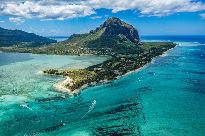 Aerial view of an African coastal area with clear turquoise water and mountainous landscape under a blue sky.