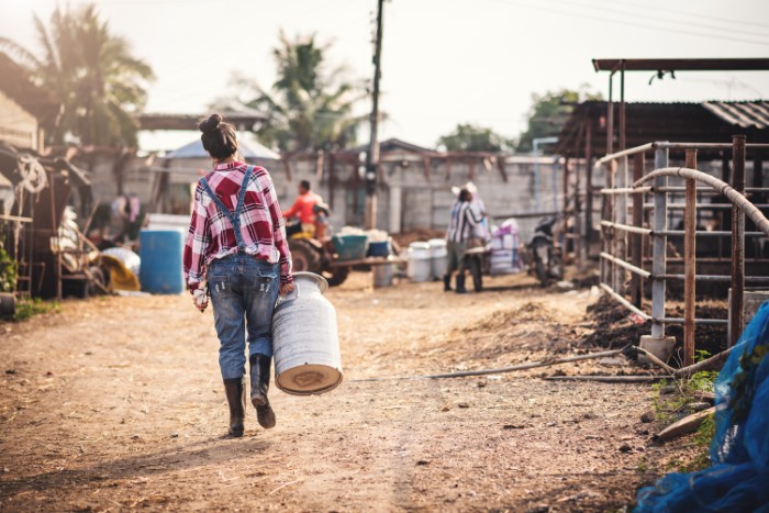 Person walking in an African village carrying a large container, reflecting on a simple lifestyle and disillusionment.