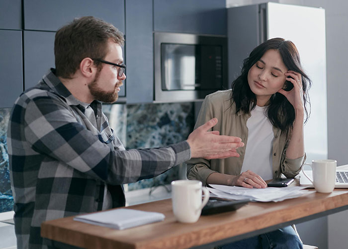 A man and woman in a kitchen having a tense discussion, illustrating people sharing insane ex stories and wild experiences.