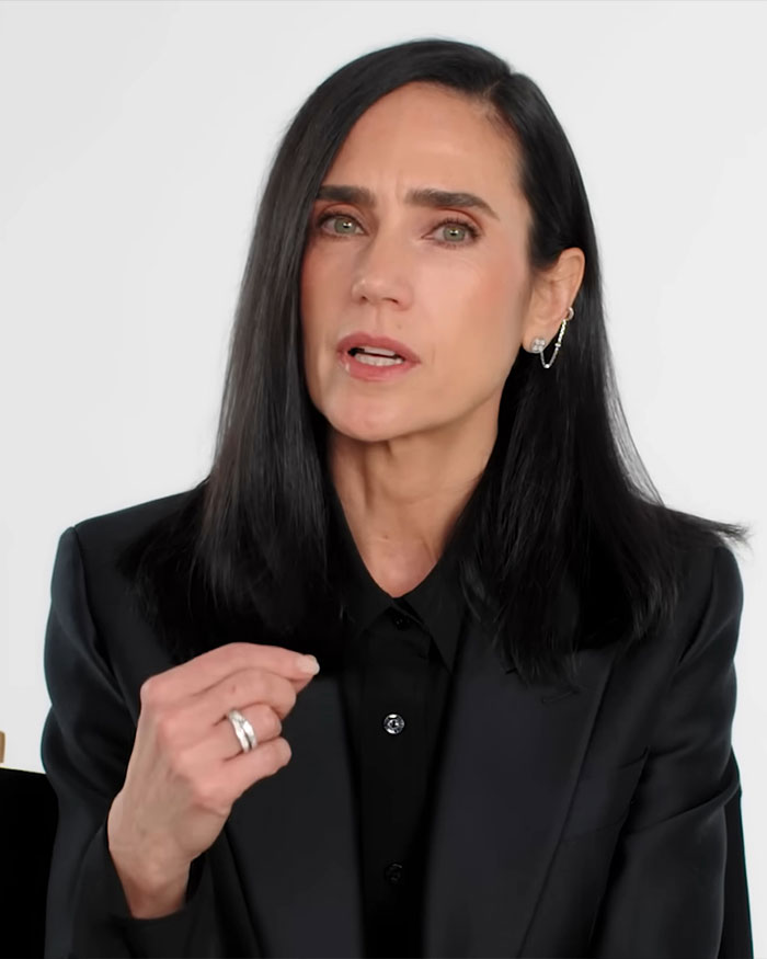 Jennifer Connelly speaking about iconic movie scene regrets in a black blazer with long dark hair on a white background. Jennifer Connelly speaking about iconic movie scene regrets in a black blazer with long dark hair on a white background.