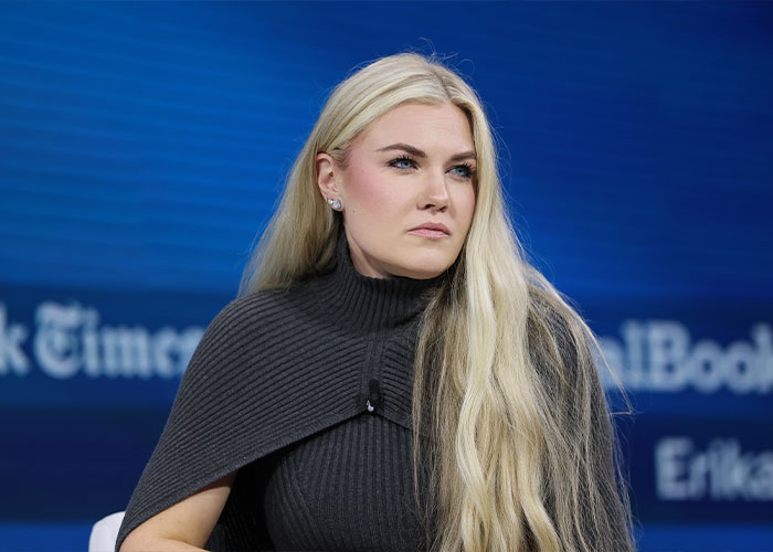 Erika Kirk with long blonde hair and gray outfit speaking at an event, related to husband Charlie's body slammed clip.