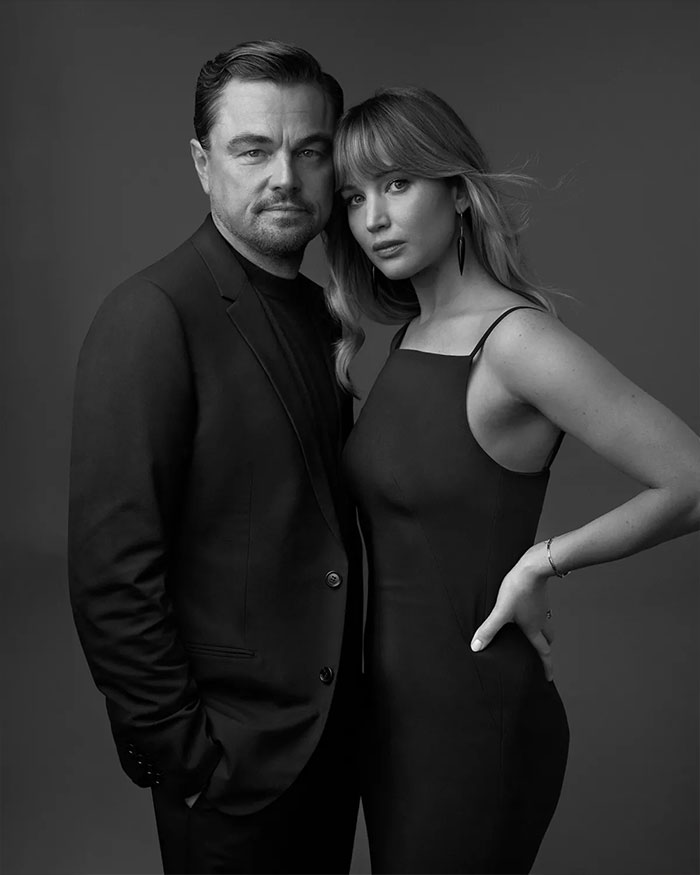 Leonardo DiCaprio and Jennifer Lawrence posing together in black outfits in a studio portrait highlighting celebrity dating history.