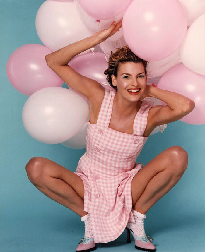 Linda Evangelista smiling in a pink dress holding pink and white balloons showcasing Coolsculpting results.