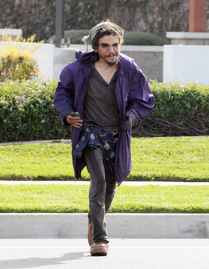 Man in worn clothes walking outdoors, highlighting dad of Nickelodeon star Tylor Chase experiencing life on the streets.