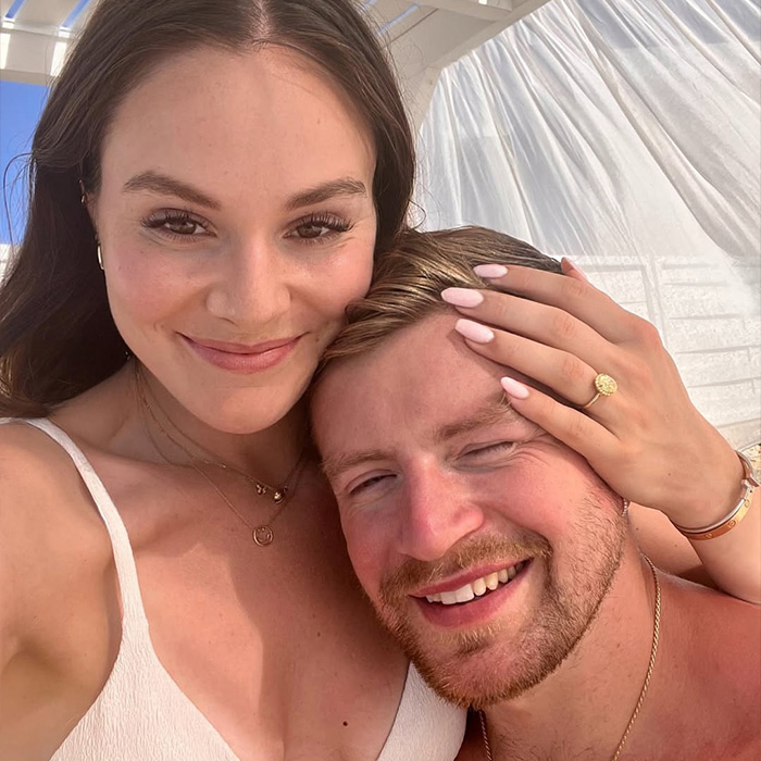 A happy couple smiling closely together with natural light highlighting their faces in a casual setting.
