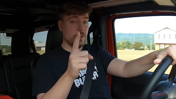 Man inside a car pointing a finger while driving, illustrating people think celebrities closet skeletons concept.