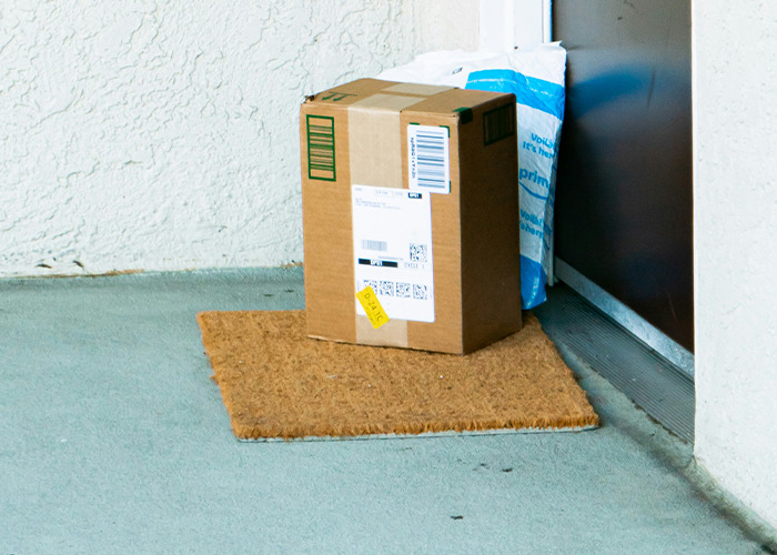 Package and mail delivery left on a doormat outside a closed front door, illustrating non-emergency situations.